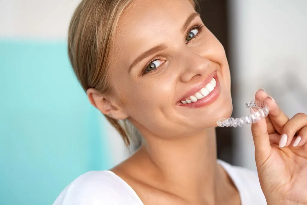 Woman smiling with transparent aligners on her hand